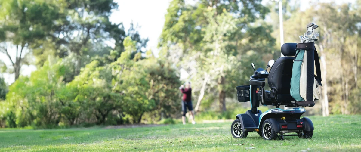 A mobility scooter on grass with its owner in the background blurry playing golf